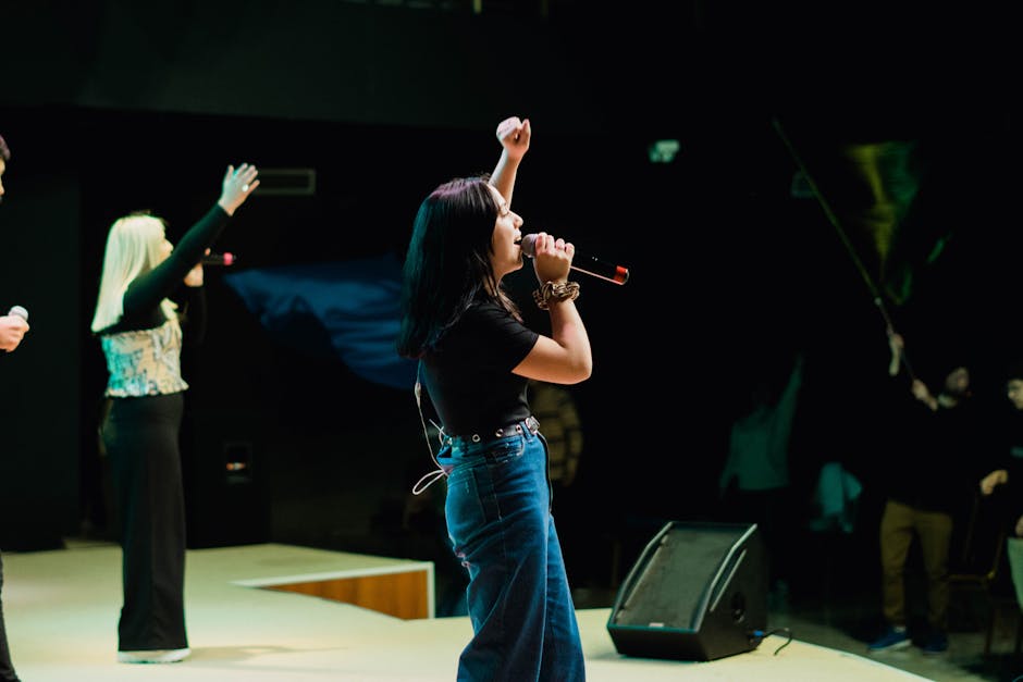 Energetic female musician singing live on stage with arm raised in front of an audience